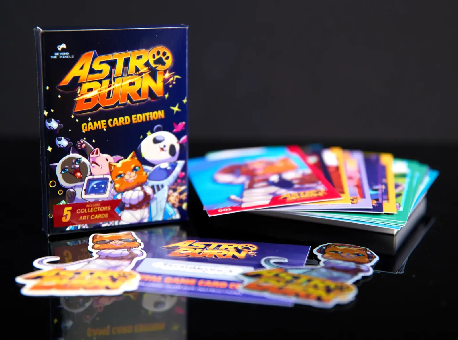 Astro Burn Game Card Edition box beside a stack of art cards and stickers